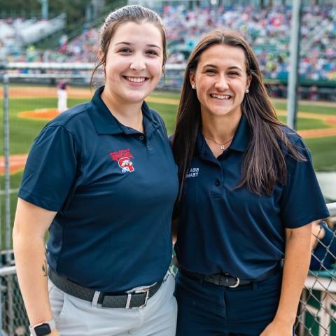 Two UNE business students pose in front of the baseball diamond at Portland's Hadlock Field